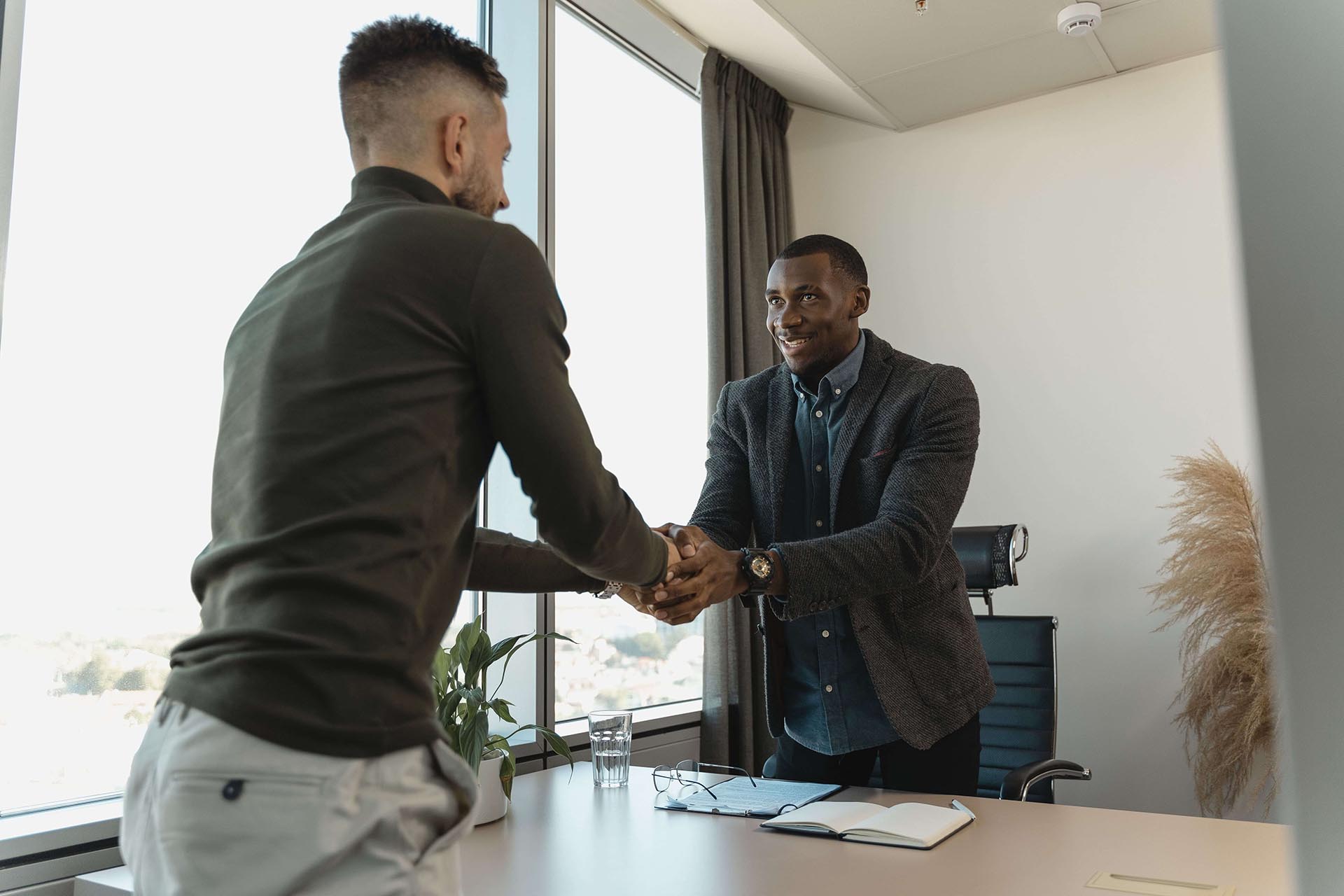 Two men shaking hands over desk