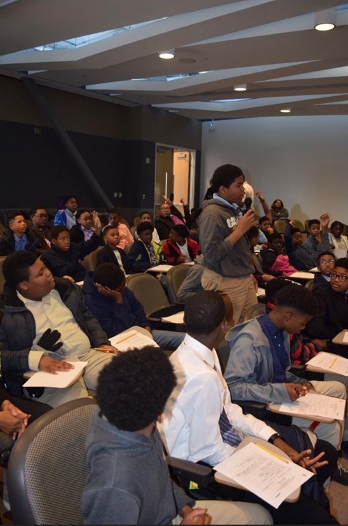 students participating in a seminar, with student standing to ask a question